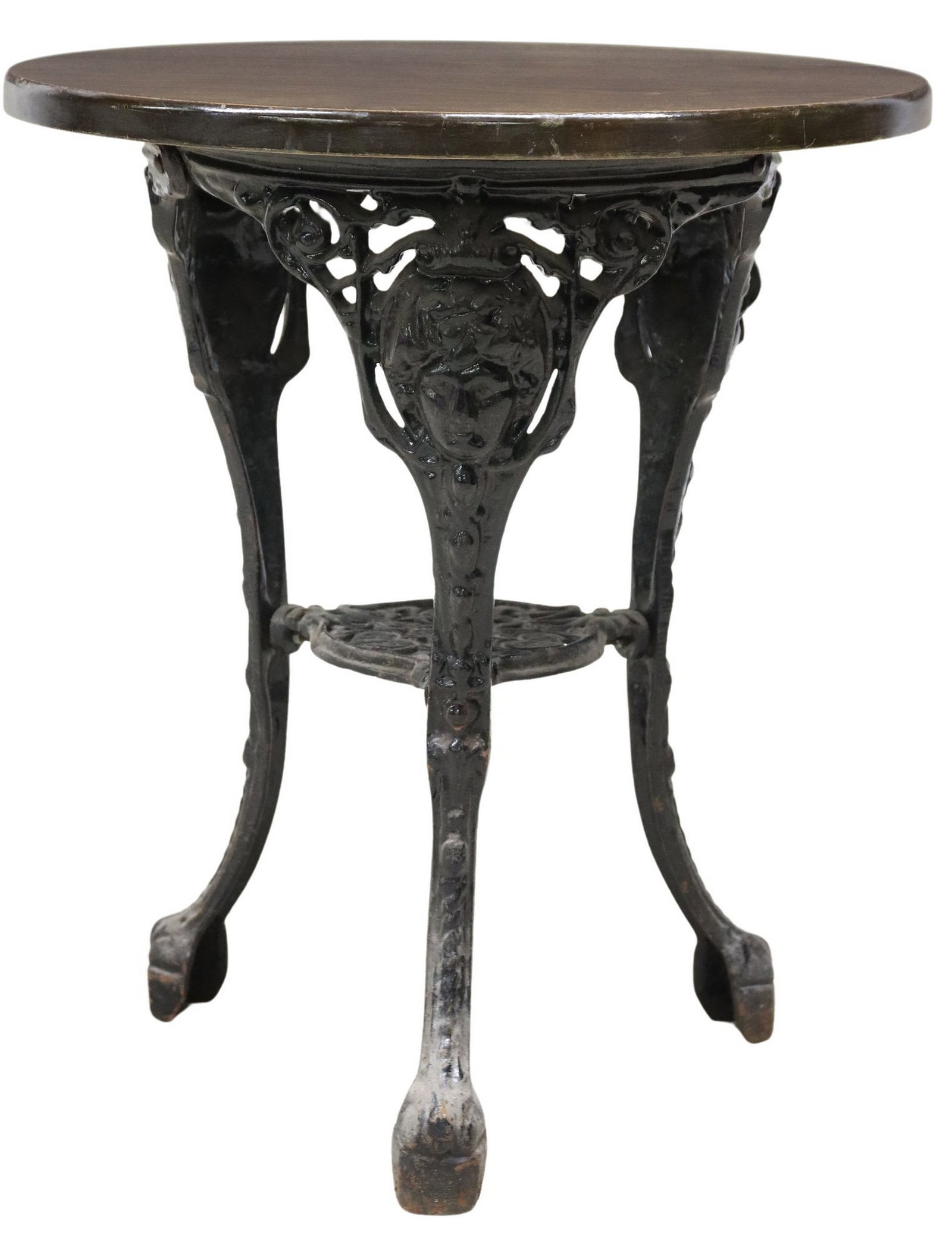 ENGLISH OAK & CAST IRON PUB TABLE: English oak and cast iron pub table, 20th c., having round top, raised on tripod frame cast with figural faces, joined by foliated medial shelf with hearts, approx 27"h, 23.25"diam