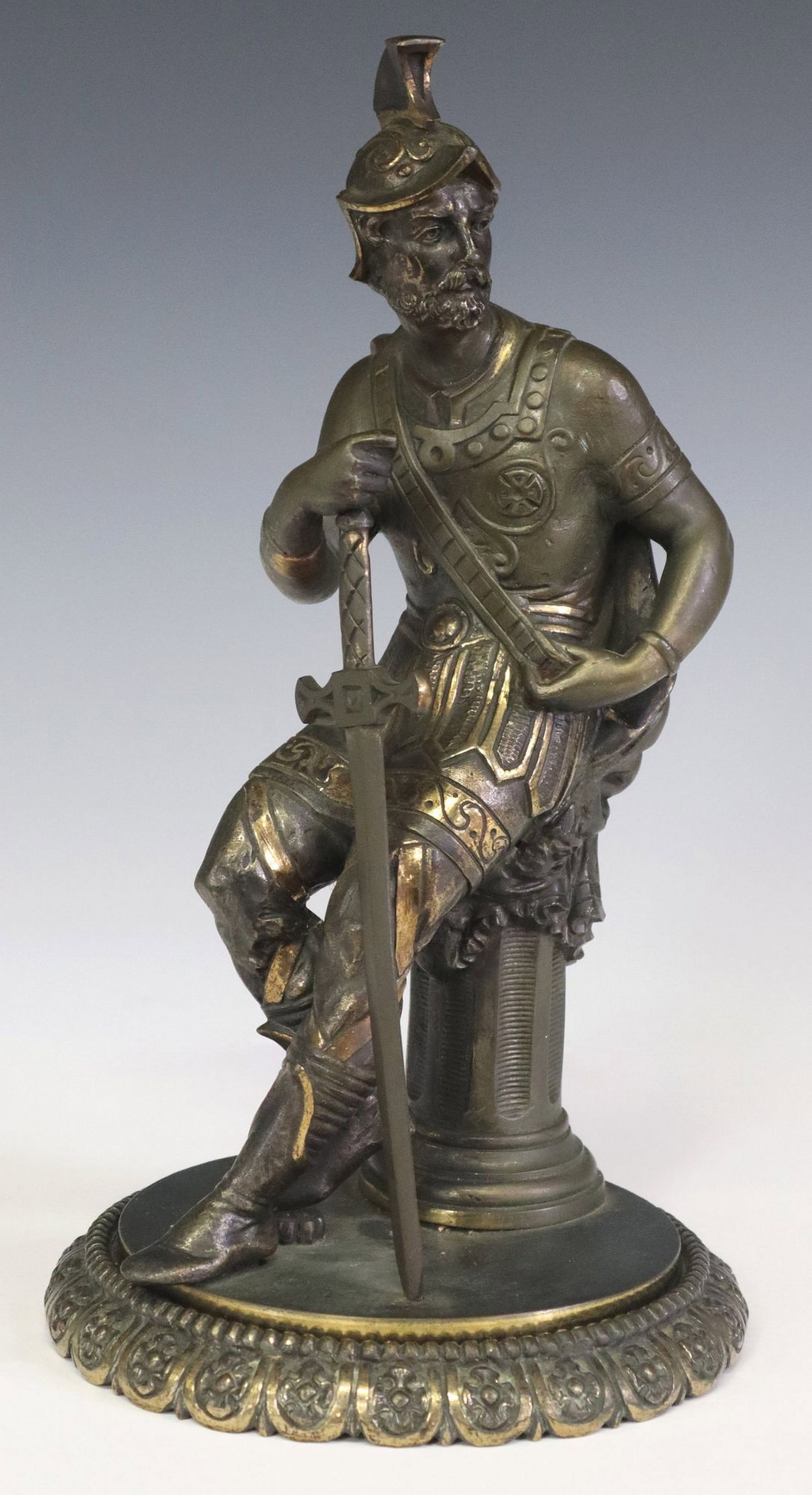 CLASSICAL STYLE PATINATED BRONZE FIGURAL SCULPTURE, ROMAN SOLDIER: Classical style patinated bronze figural sculpture, Seated Roman Warrior, depicting a male figure donning Roman style armor and sword, seated on fluted columnar pedestal, rising on circular base 