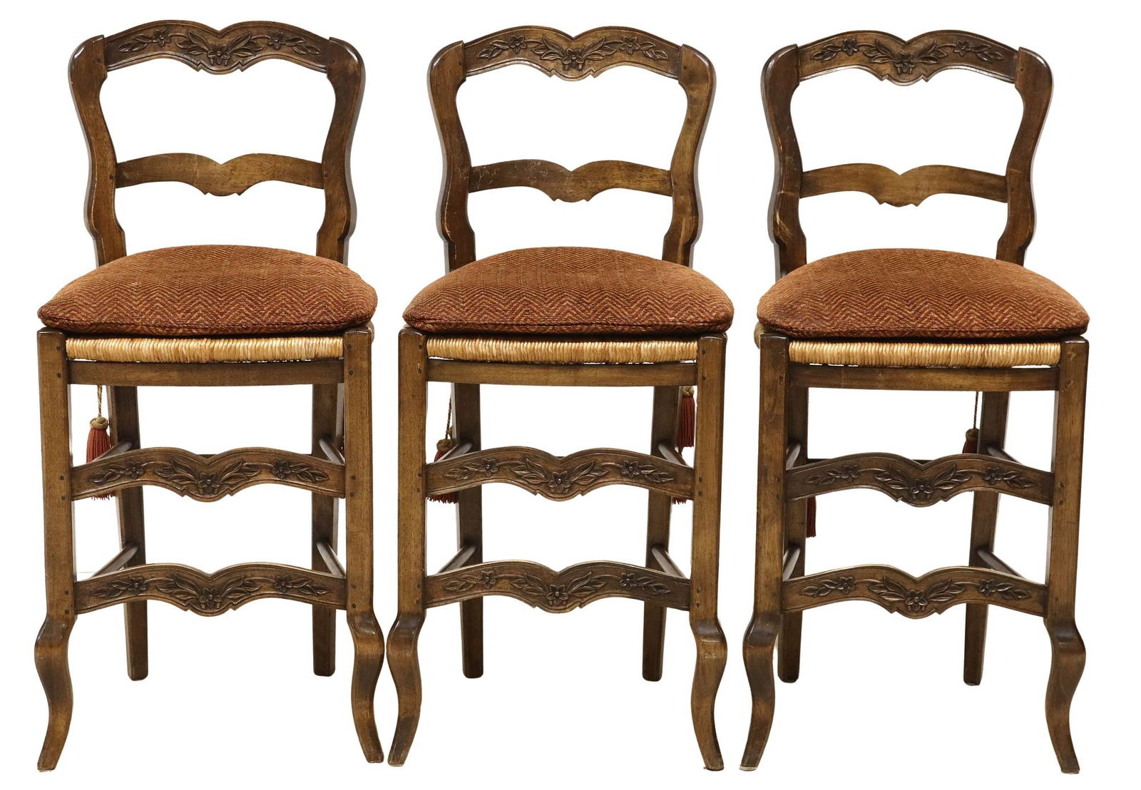 (3) PROVINCIAL COUNTER-HEIGHT STOOLS WITH SCALAMANDRE CUSHIONS: (lot of 3) Provincial counter-height stools, 20th c., ladder back with floral carving, woven rush seat, loose seat cushion in Scalamandre upholstery fabric, secured with tasseled cords, on stretcher-j