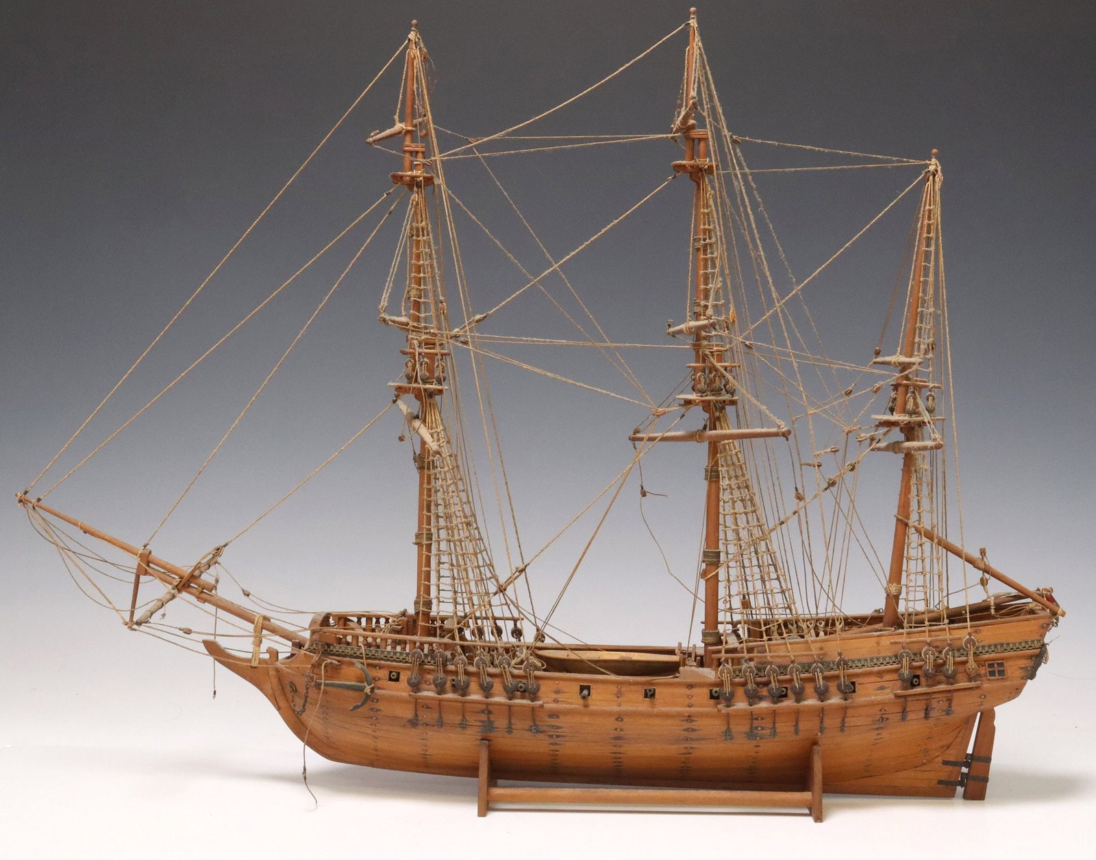 FULLY RIGGED THREE-MAST MODEL SAILING SHIP WITH STAND: Model sailing ship, 20th c., three-masted single hull vessel with cannons and corded rigging, accompanied by display stand, some typical loss to rigging, approx 19"h, 25"w, 4.5"d, 