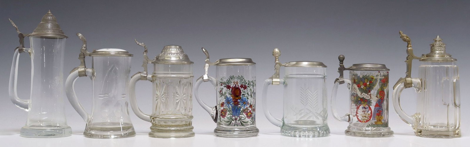 (7) GERMAN PEWTER-MOUNTED GLASS STEINS: (lot of 7) German glass steins, highlights include: (1) cut glass stein, inset porcelain cover with facsimile signature, underside of cover stamped Normann/ Nurnberg, (2) steins with transferred 