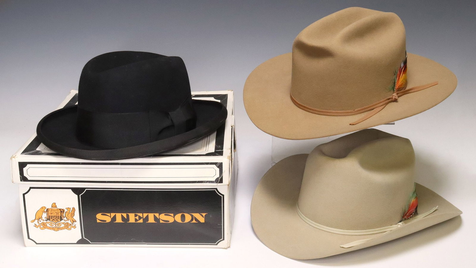 (3) STETSON TAN 4X BEAVER FELT COWBOY HATS & BLACK WOOL FEDORA: (lot of 3) Stetson felt hats, including: (2) 4X beaver felt cowboy hats, each having ribbon hatband with feather, 3" brim, worn brown leather sweatband, cream satin lining with branded liner tipp