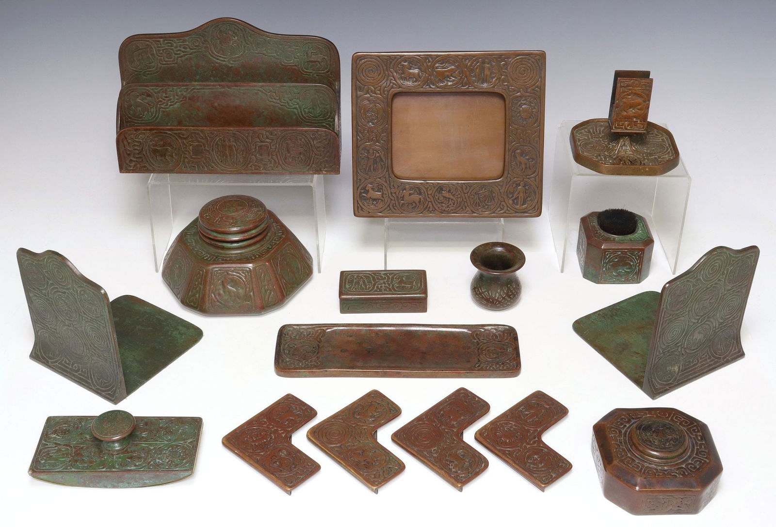 (16) TIFFANY STUDIOS 'ZODIAC' PATINATED BRONZE DESK SET: (lot of 16) Patinated bronze desk set, Tiffany Studios, New York, early 20th c., in the "Zodiac" pattern, including: (pair) bookends, numbered 1091, (1) large inkwell, with glass liner, numb