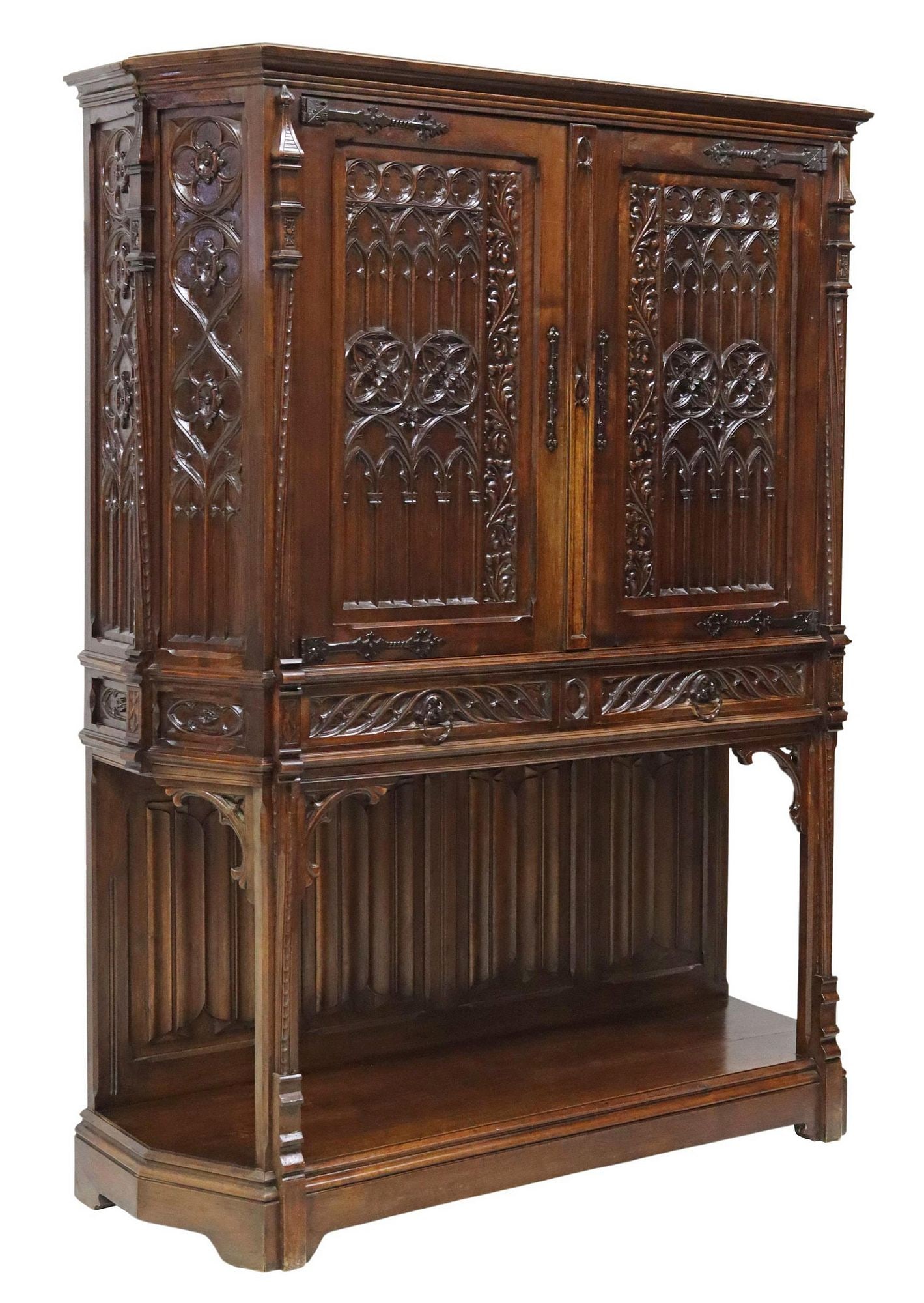 FRENCH GOTHIC REVIVAL CARVED WALNUT CREDENCE CUPBOARD: French Gothic Revival walnut credence cupboard, late 19th c., carved tracery and architectural motifs, two doors on iron strap hinges above two frieze drawers, carved linenfold back panels, the platfo