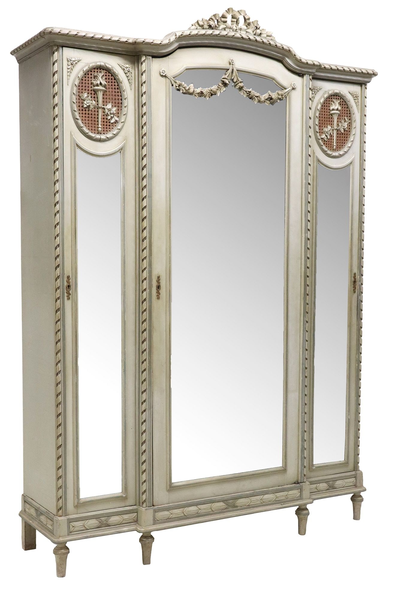 LOUIS XVI STYLE PAINT-DECORATED MIRRORED ARMOIRE: French Louis XVI style paint-decorated armoire, 19th c., having ribbon and foliate crest on molded cornice, large central door, flanked by narrow side cabinets with ovular caned panel centering torch 