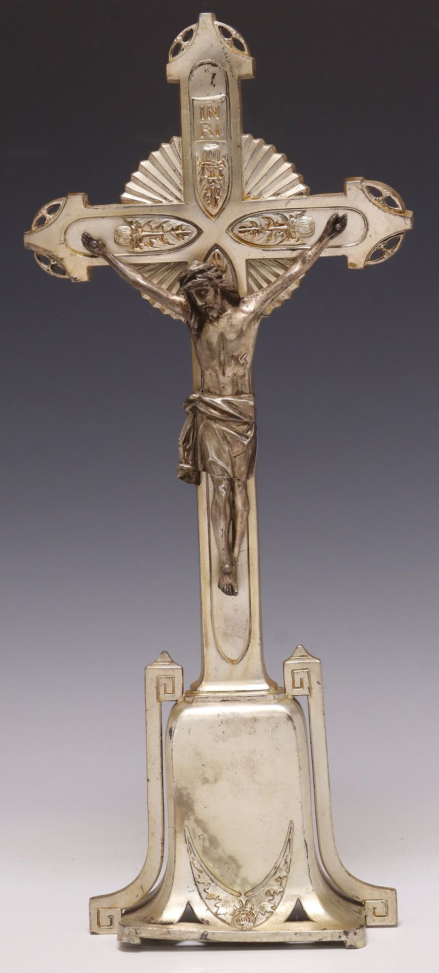 SILVER-TONE METAL RELIGIOUS ALTAR CRUCIFIX: Silver-tone metal altar crucifix, early 20th c., centering the Corpus Christi, pierced and incised foliate designs, ending on shaped base, approx 19 5/8"h, 8.25"w, 3.5"d, 3.6lbs 
