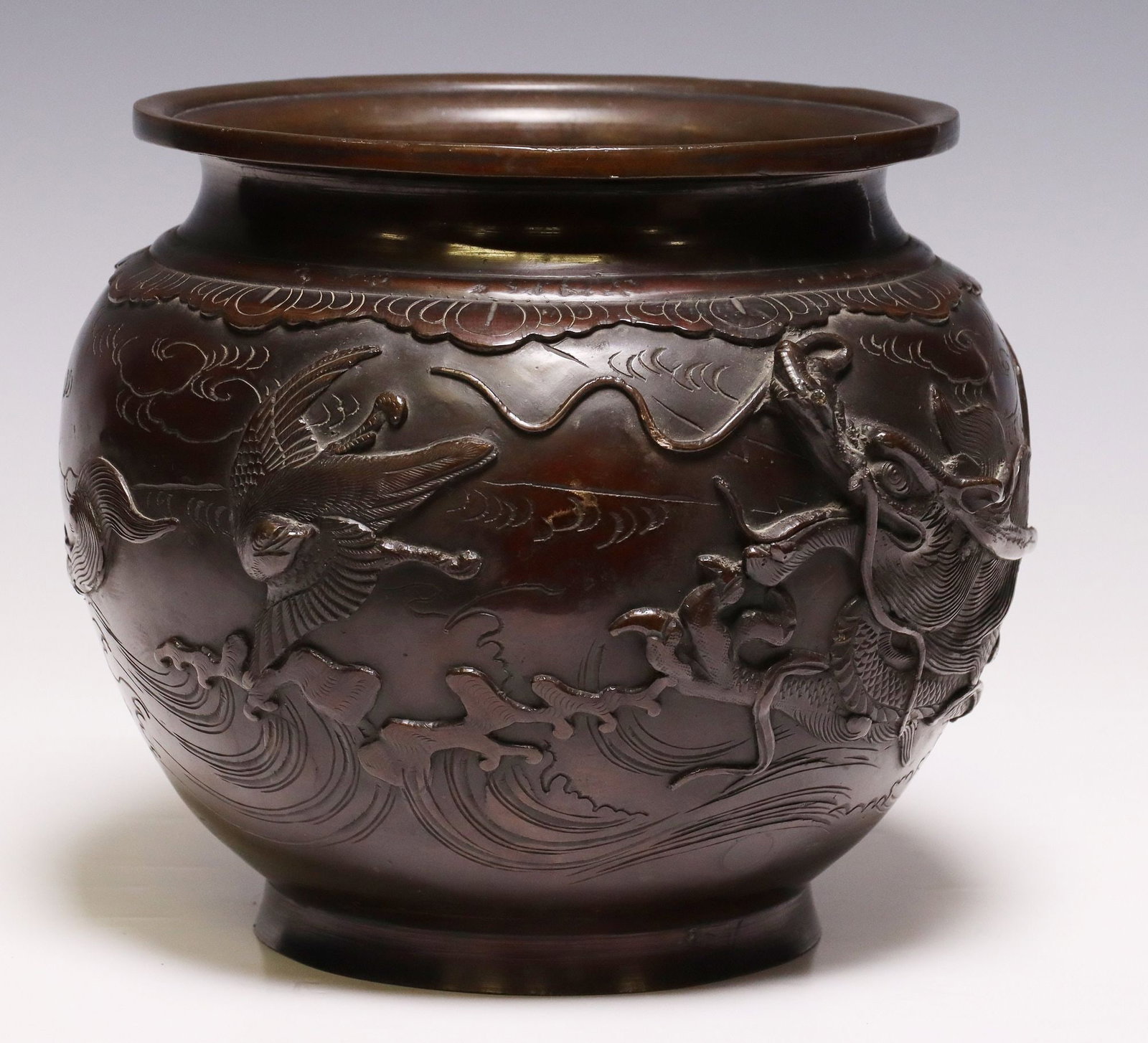 YOSHIDA ZO MEIJI PERIOD PATINATED BRONZE 'DRAGON' VASE: Japanese bronze vase, Meiji period, flared rim over tapering globular body, rising on round foot, the basin exterior decoration with serpentine dragon and phoenix in relief among auspicious clouds, in