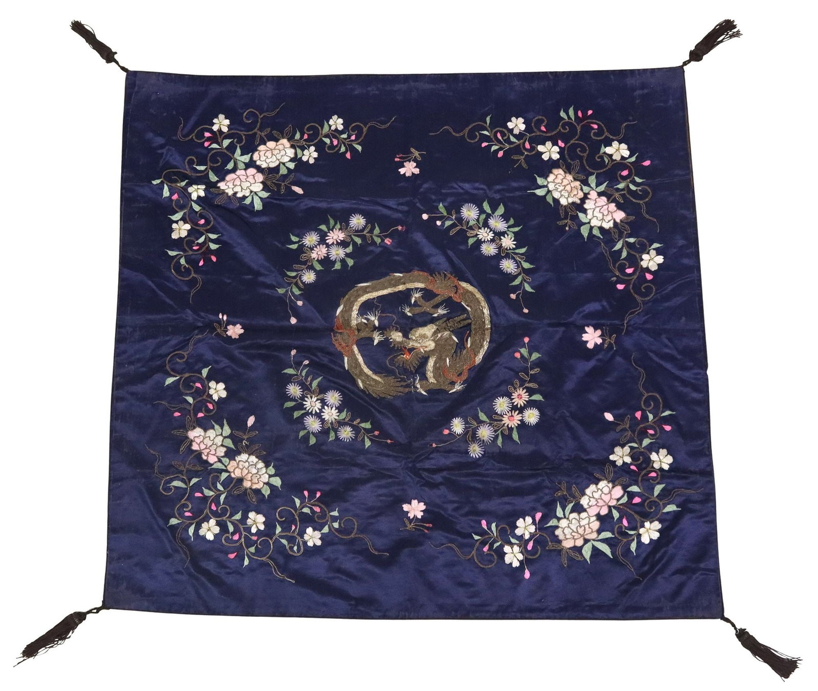 CHINESE SILK EMBROIDERY DRAGON: Chinese silk embroidery, central image of a dragon executed in couched metal threads, framed by pink and white flowers, against a blue silk ground, with tassels at the four corners, thread loss/ 