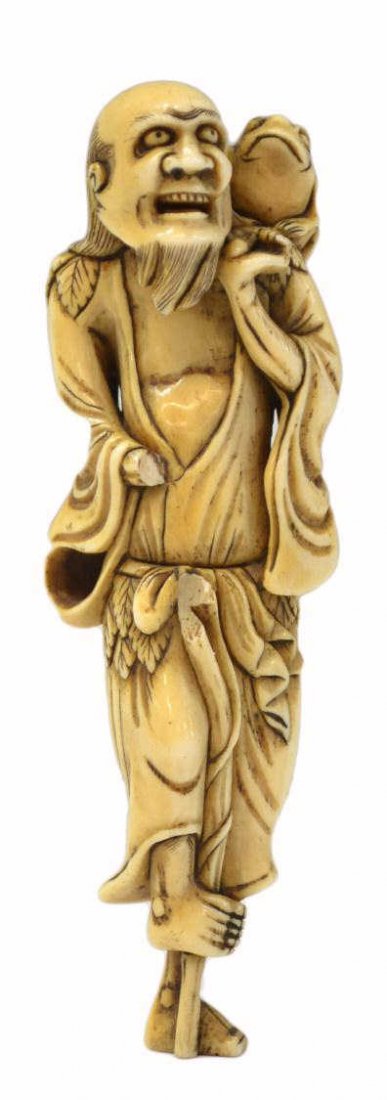 JAPANESE FIGURAL IVORY SASHI NETSUKE, EDO PERIOD: *International shipping is not available on this lot* Japanese tinted ivory sashi netsuke (toggle), Edo period (1615-1868) carved as the Chinese immortal Gama sennin standing with this three-legged to