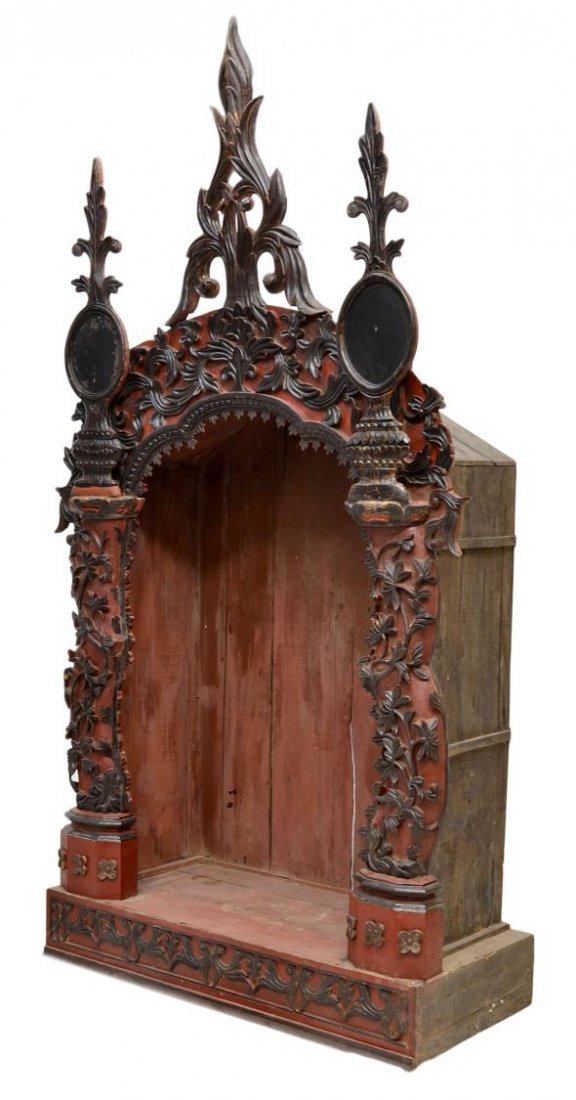 LARGE FRENCH COLONIAL PARCEL GILT ALTAR NICHE: Large French Colonial parcel gilt carved altar niche in red and black paint, 19th c., the impressive architectural case in the Gothic style with towering crest flanked by spires, scalloped central arc