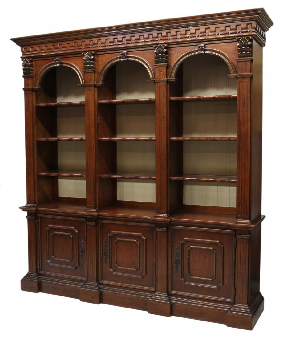 A CARVED MAHOGANY OPEN BOOKCASE / DISPLAY: Carved mahogany bookcase display, the overhang cornice above a dentil carved frieze, pilasters surmounted by Corinthian capitals separate three arched display sections set with wood shelving with glas