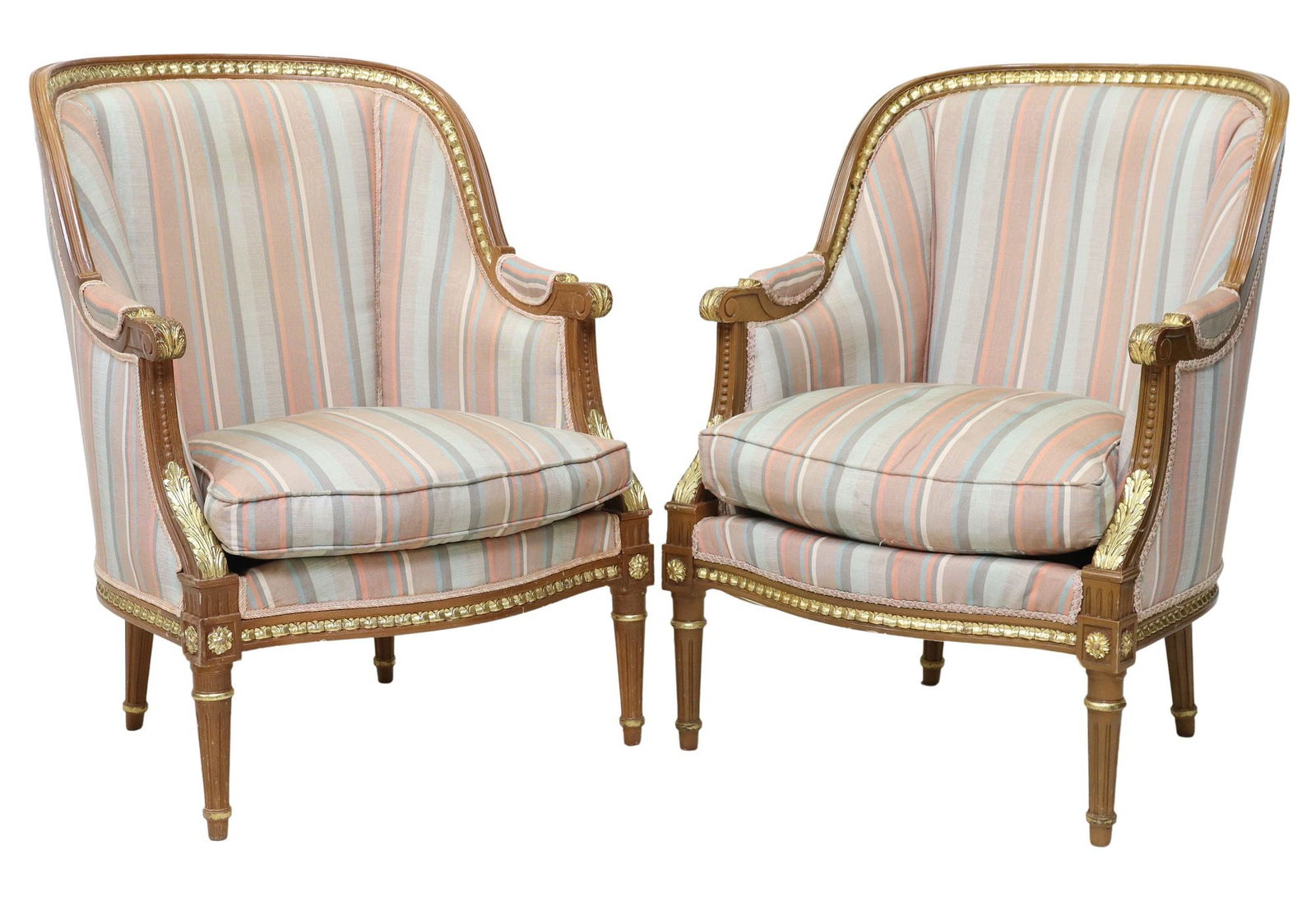 (2) LOUIS XVI STYLE PARCEL-GILT & UPHOLSTERED BERGERES: (pair) Louis XVI style upholstered armchairs, 20th c., having molded frame with parcel gilt accents, rounded back and arms, removable seat cushion, in striped fabric upholstery, with ribbon trim,