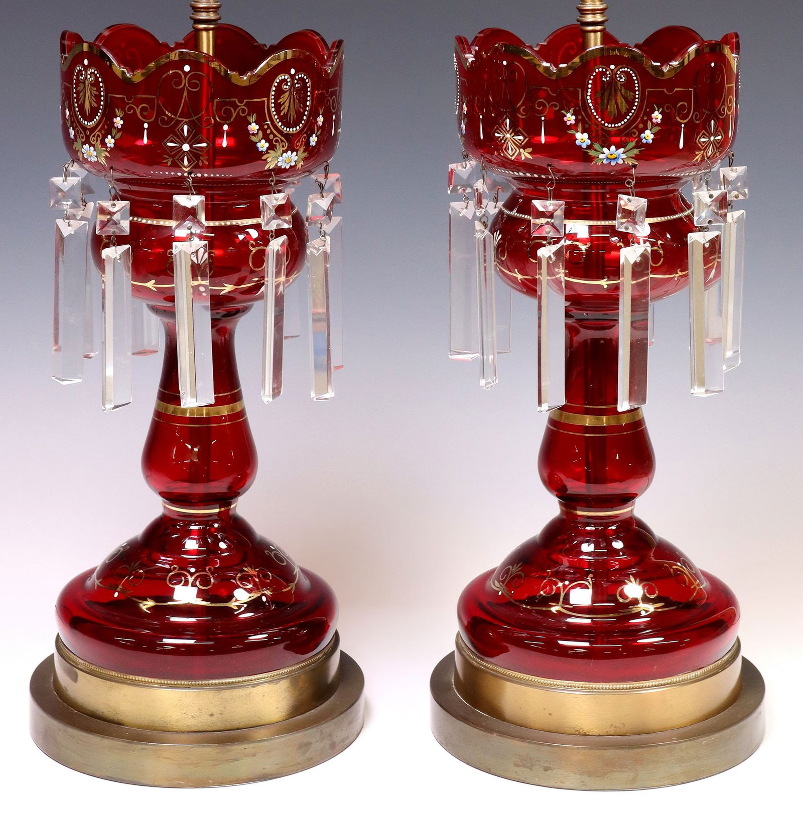 (2) PARCEL-GILT & ENAMELED RUBY GLASS & CRYSTAL MANTEL LUSTER TABLE LAMPS: (pair) Parcel gilt ruby glass mantle lusters, now fashioned as table lamps, 20th c., each having flared rim over bulbous body, with scrolled foliates and enameled floral motifs, hung with faceted crys