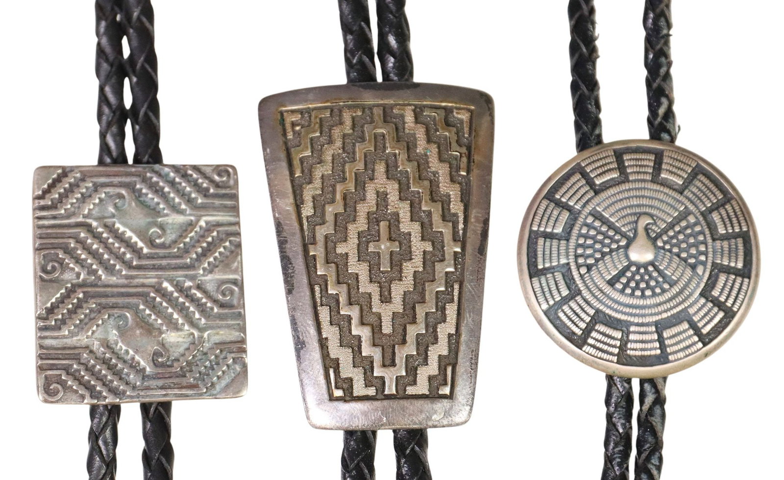 (3) TOMMY JACKSON (NAVAJO, B.1958) & OTHER SILVER OVERLAY BOLO TIES: (lot of 3) Native American silver overlay bolo ties, each with silver tips, on braided black leather cord, including: (1) sterling bolo, signed T. Jackson (Tommy Jackson, Navajo/ Dine, active in 