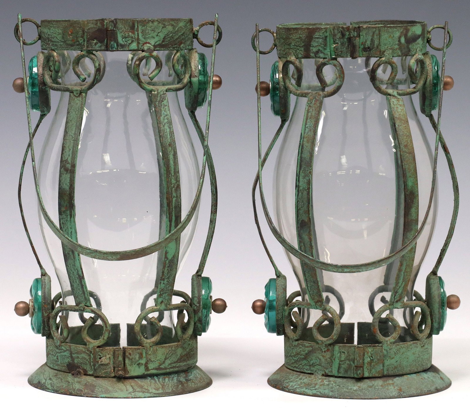 (2) RUSTIC VERDIGRIS PATINA HANGING CANDLE LANTERNS: (pair) Rustic hanging candle lanterns, 20th c., in a verdigris finish, arched handle over caged body, with scrolled accents and turquoise colored and molded glass plaques, hinged f