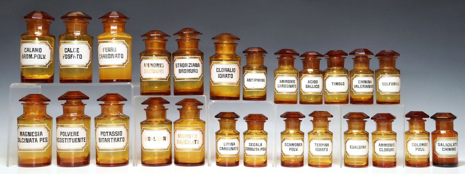 (25) ITALIAN ORANGE GLASS APOTHECARY / PHARMACY JARS WITH STOPPERS: (lot of 25) Italian orange glass apothecary/ pharmacy jars, early 20th c., each with faceted stopper, retaining adhesive identification label, varied sizes, some with unknown residue to interior,