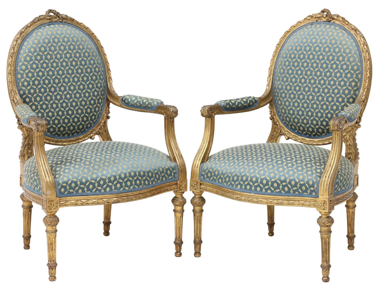 (2) FRENCH LOUIS XVI STYLE GILTWOOD UPHOLSTERED FAUTEUILS: (pair) French Louis XVI style giltwood armchairs/ fauteuils, early 20th c., each having foliate crest, over molded frame with beaded trim, in later patterned fabric upholstery, rising on fluted tapere