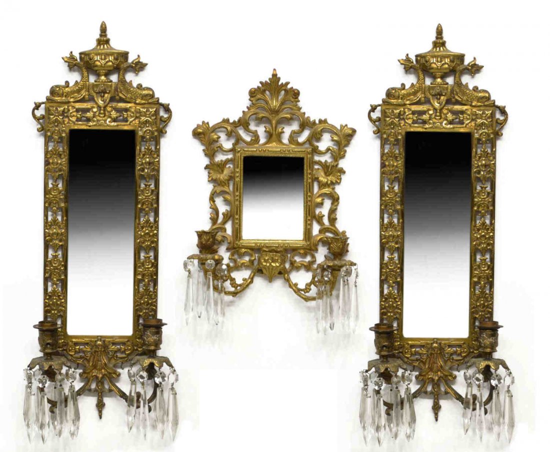 (3) GILT METAL MIRRORED AND PRISM WALL SCONCES: (lot of 3) Gilt metal two-light wall girandole mirror sconces, in the style of Bradley and Hubbard, comprising: (1) scrolled foliate framed enclosing a beveled mirror, two branching arms holding flori