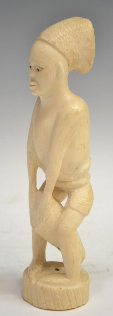 AFRICAN CARVED IVORY TRIBAL FIGURE PLAYING DRUM: *International shipping is not available on this lot* African carved ivory tribal figure, likely Zulu, posed in a standing position hands upon a drum, tinted eyes, circular base, some wear, split to d
