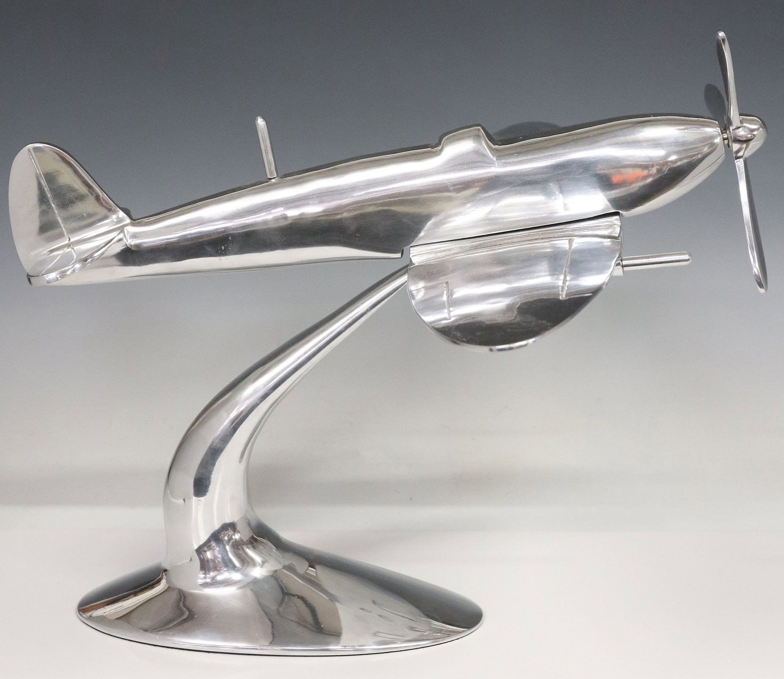 LARGE CHROMED METAL SPITFIRE AIRPLANE MODEL, 17"H: Large chromed metal airplane model, late 20th c., depicting a Spitfire aircraft, with movable propeller, on integral tapered stand, approx 17"h, 20"w, 24"d, 10lbs **Note: matching airpl