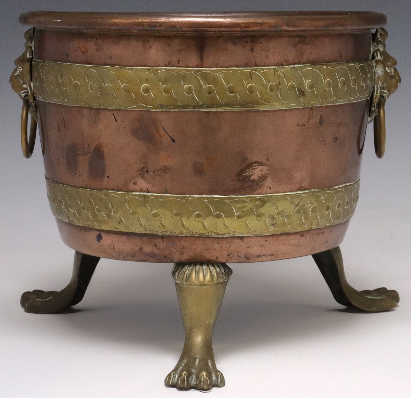 ENGLISH VICTORIAN COPPER AND BRASS JARDINIERE / PLANTER: English Victorian copper and brass planter/ jardiniere, late 19th c., having dual lion mask ring handles and banded sides, rising on paw feet, approx 9.5"h, 12.25"w, 12.25"d, 6lbs