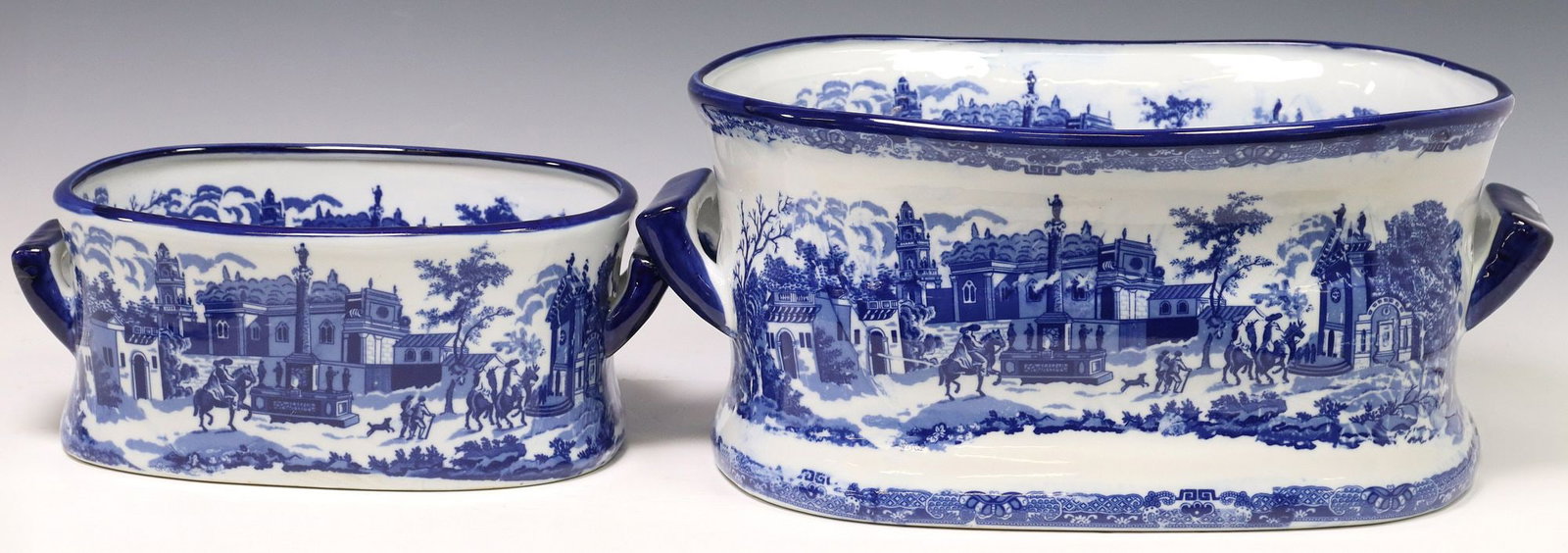 (2) BLUE & WHITE TRANSFERWARE STREET SCENE FOOTBATHS: (lot of 2) Blue and white transferware footbaths, 21st c., with transferred street scene in a townscape, dual side handles, marked Victoria Ware underfoot, largest: approx 8 3/8"h, 19.25"w, 