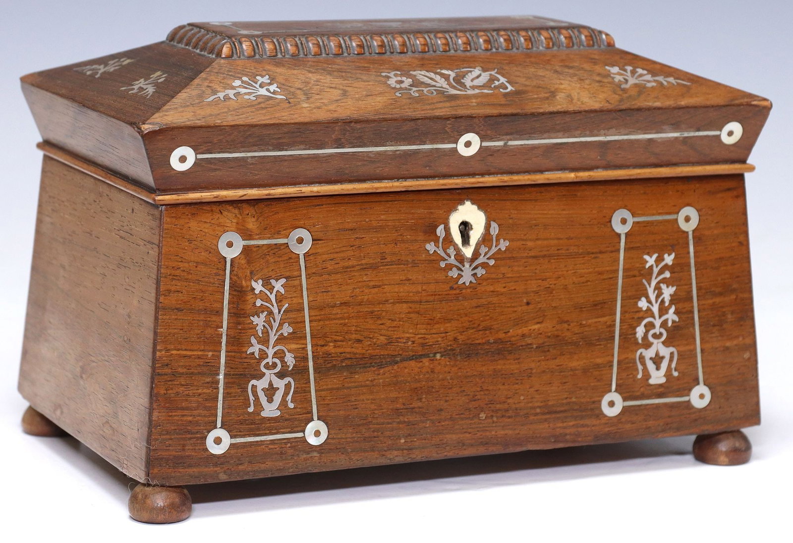 ENGLISH REGENCY MOTHER-OF-PEARL INLAID ROSEWOOD TEA CADDY: English Regency period rosewood tea caddy, early 19th c., of sarcophagus form with scrolling foliate mother of pearl inlay, hinged top opening to divided interior accommodating two tea boxes, rising o