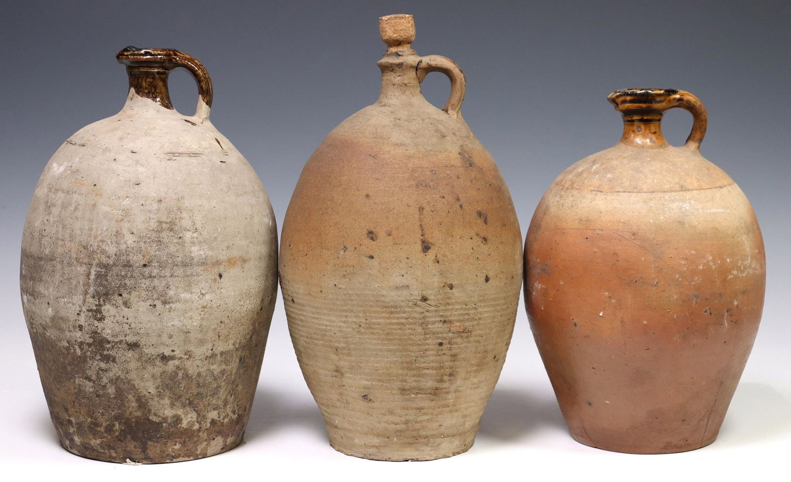 (3) FRENCH PROVINCIAL STONEWARE PITCHERS / WATER JUGS: (lot of 3) French Provincial stoneware pitchers/ water jugs, each having narrow spout and curved handle, over tapered body, (one) intact with inherent hairline to handle, largest: approx 14"h, 7.