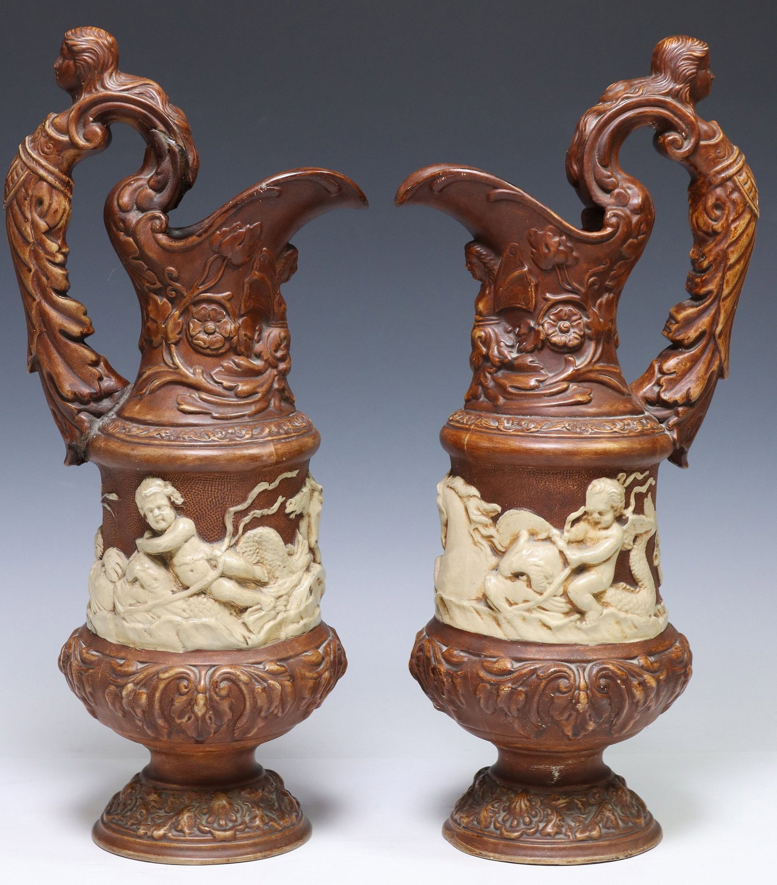 (2) LARGE NEOCLASSICAL STYLE CAST WATER EWERS, 20.5"H: (pair) Large Neoclassical style cast composite water ewers/ pitchers, 20th c., each having scrolled handle with mask-form end, over central procession depicting various allegorical figures and mythica