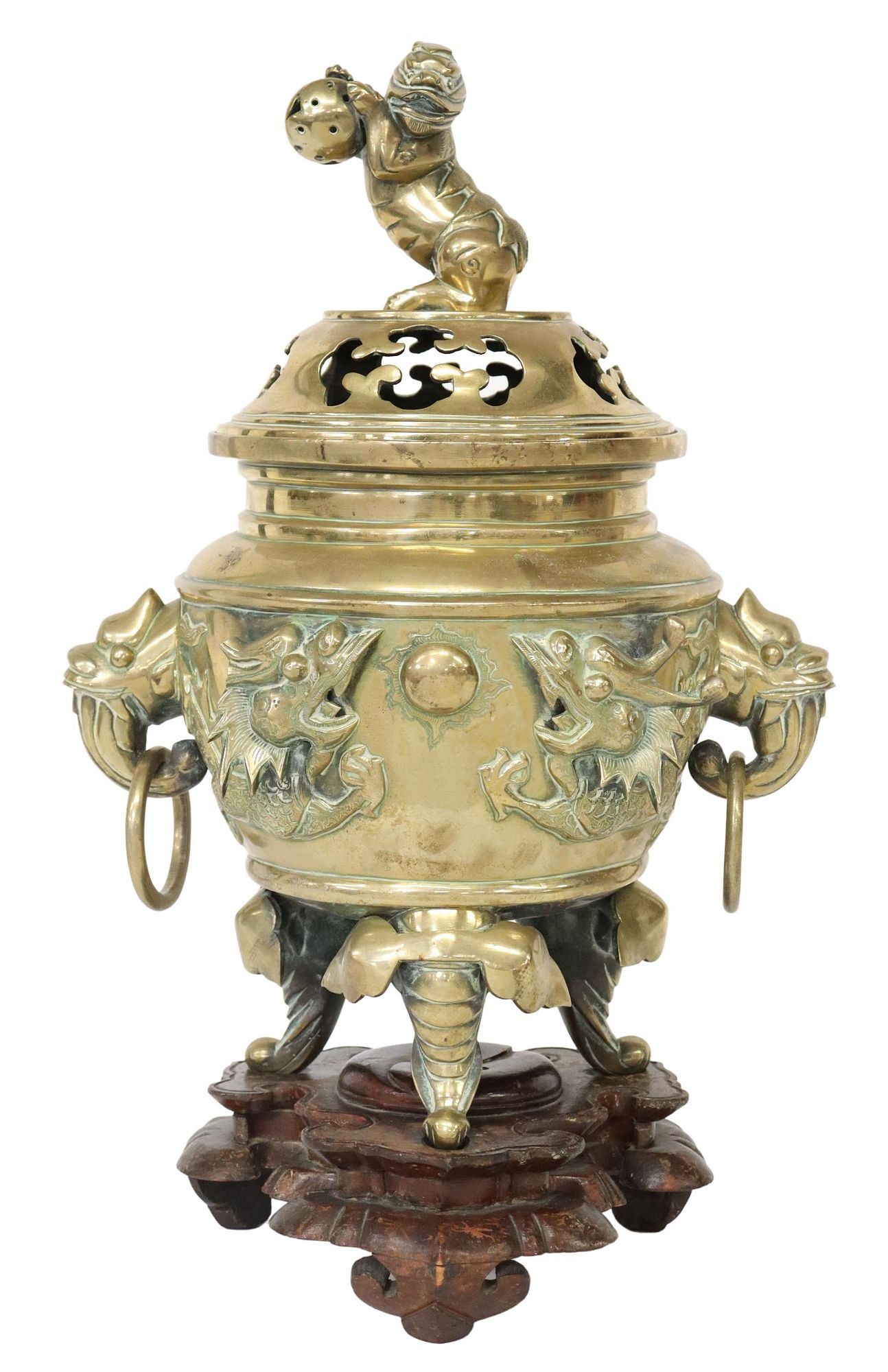 CHINESE BRONZE TRIPOD CENSER & COVER ON RUYI STAND: Chinese bronze tripod censer/ incense burner, domed and pierced cover with a Buddhist lion finial, over body ornamented with pair of dragons pursuing the flaming pearl, beast mask and ring h