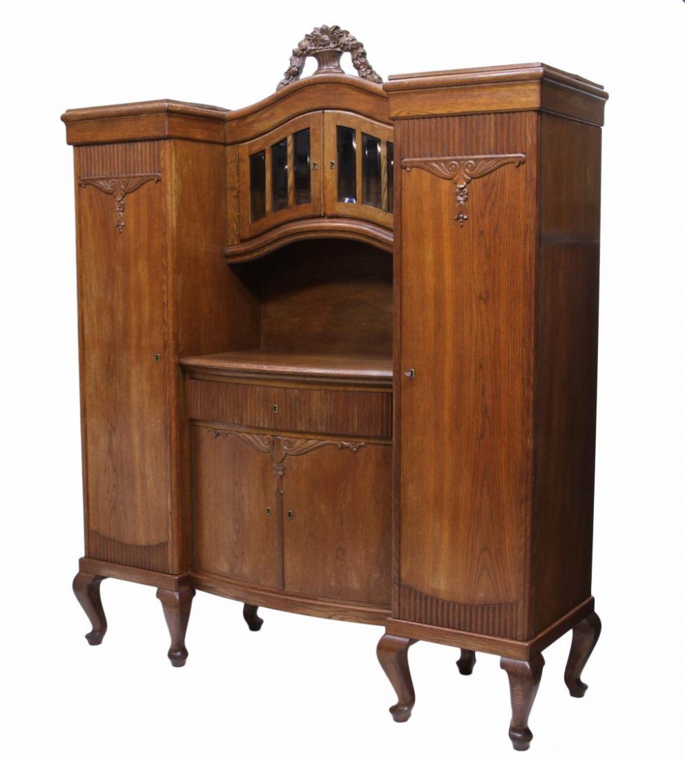 ANTIQUE OAK FINISH SIDEBOARD, 19TH C.: Antique oak finish sideboard, 19th c., an arched center back, the cornice with carved flowers and vase over a two door beveled glass display, below is a bow front work surface with frieze drawer and t