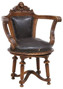 FRENCH CARVED WALNUT LEATHER UPHOLSTERED SWIVEL ARMCHAIR: French carved walnut swivel desk chair, 19th c., having figural face crest, padded back and seat in leather upholstery, rising on turned supports, joined by X stretcher, typical wear and some los