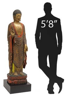 LARGE CHINESE PARCEL GILT CARVED HARDWOOD BUDDHA ON STAND, 64"H: Large Chinese carved hardwood figure, depicting the Buddha standing in the Varada mudra, in a parcel gilt and polychromed gesso finish, with hair arranged in tight curls, elongated earlobes and&n