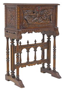 SPANISH RENAISSANCE REVIVAL VARGUENO ON STAND: Spanish Renaissance Revival bargueno/ vargueno, early 20th c., the fall-front panel carved with grotesque figures, enclosing an interior gallery with central niche framed by four small drawers, on tre