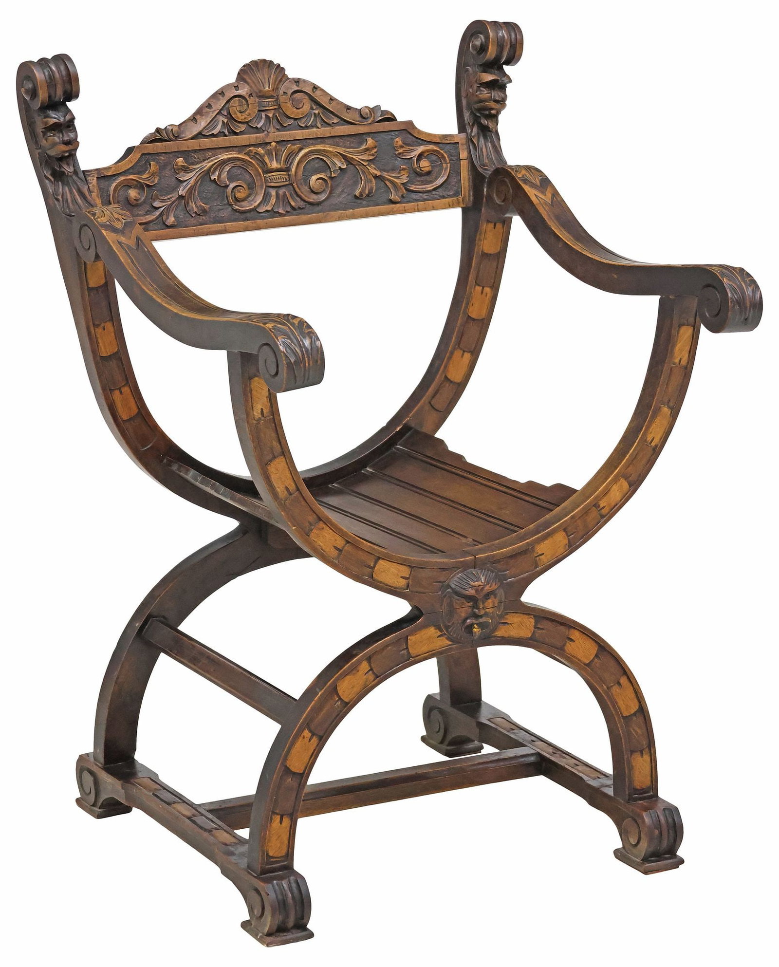 SPANISH RENAISSANCE REVIVAL CARVED WALNUT CURULE CHAIR: Spanish Renaissance Revival walnut savonarola armchair, 19th c., having carved fanned crest, over foliated scrollwork, flanked by scrolled grotesque mask finials, slatted seat, on curule base with fig