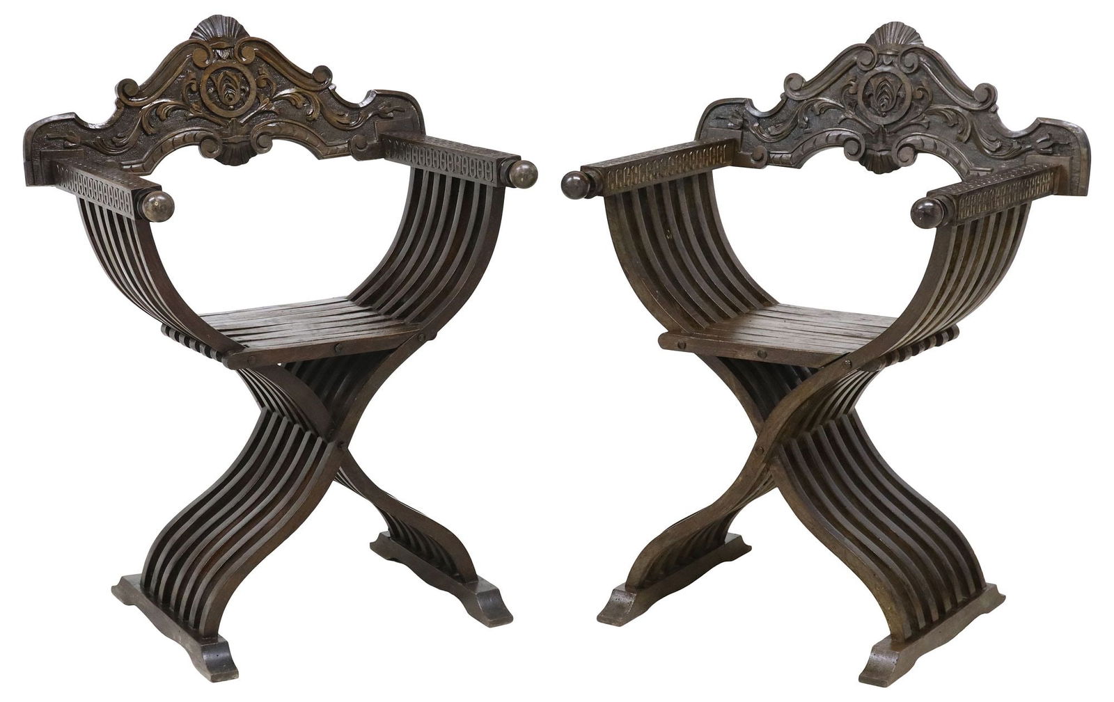 (2) ITALIAN RENAISSANCE REVIVAL CARVED SAVONAROLA CURULE CHAIRS: (pair) Italian Renaissance Revival carved Savonarola chairs, early 20th c., having fanned foliate crest, over folding slatted frame, knobbed arms with running ornamentation, rising on curule base, end