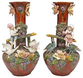 (2) FRENCH BARBOTINE POLYCHROME MAJOLICA FIGURAL VASES, 20 7/8"h: (pair) French Barbotine tin-glazed earthenware/ majolica vases, early 20th c., having long neck over bulbous body, mottled brown glaze with applied flowers and leaves, depicting a boy and girl feeding
