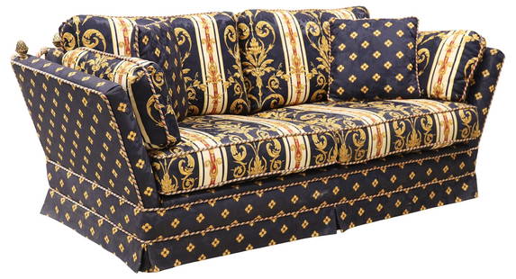 CUSTOM UPHOLSTERED KNOLE-STYLE SOFA: Knole-style sofa, 20th c., back and seat cushions in a Versace-style printed textile, stationary arms with gilt-metal pineapple finials, skirted base concealing wood block feet, approx 29"h, 79"w, 37"
