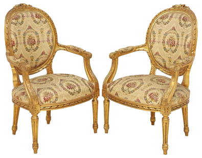 (2) FRENCH LOUIS XVI STYLE SILK-UPHOLSTERED GILTWOOD FAUTEUILS: (pair) French Louis XVI style giltwood armchairs/ fauteuils, early 20th c., having carved foliate crest, over round back and seat in a fine silk upholstery with tapestry style floral embroidery, twist