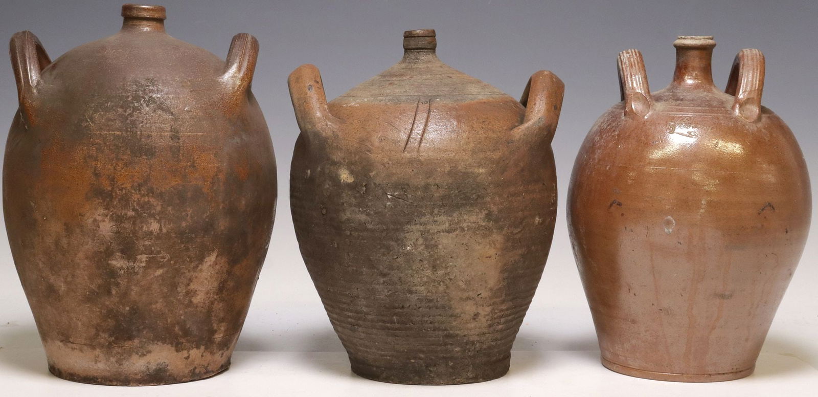 (3) FRENCH PROVINCIAL STONEWARE OIL JUGS: (lot of 3) French Provincial stoneware oil jugs, each with dual side handles over tapered body, one stamped "5" and inscribed "Bonny?" at side, largest: approx 13.25"h, 8"diam, 22.75lbs total