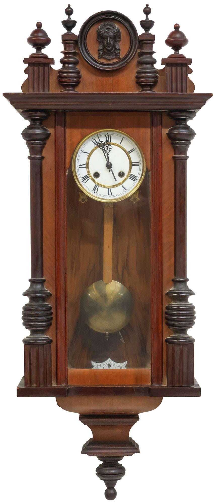 CONTINENTAL CARVED WALNUT REGULATOR WALL CLOCK: Continental carved walnut regulator wall clock, late 19th c., having fluted crest with central portrait plaque, flanked by turned finials, above glazed case, white enameled dial with Roman numeral hou