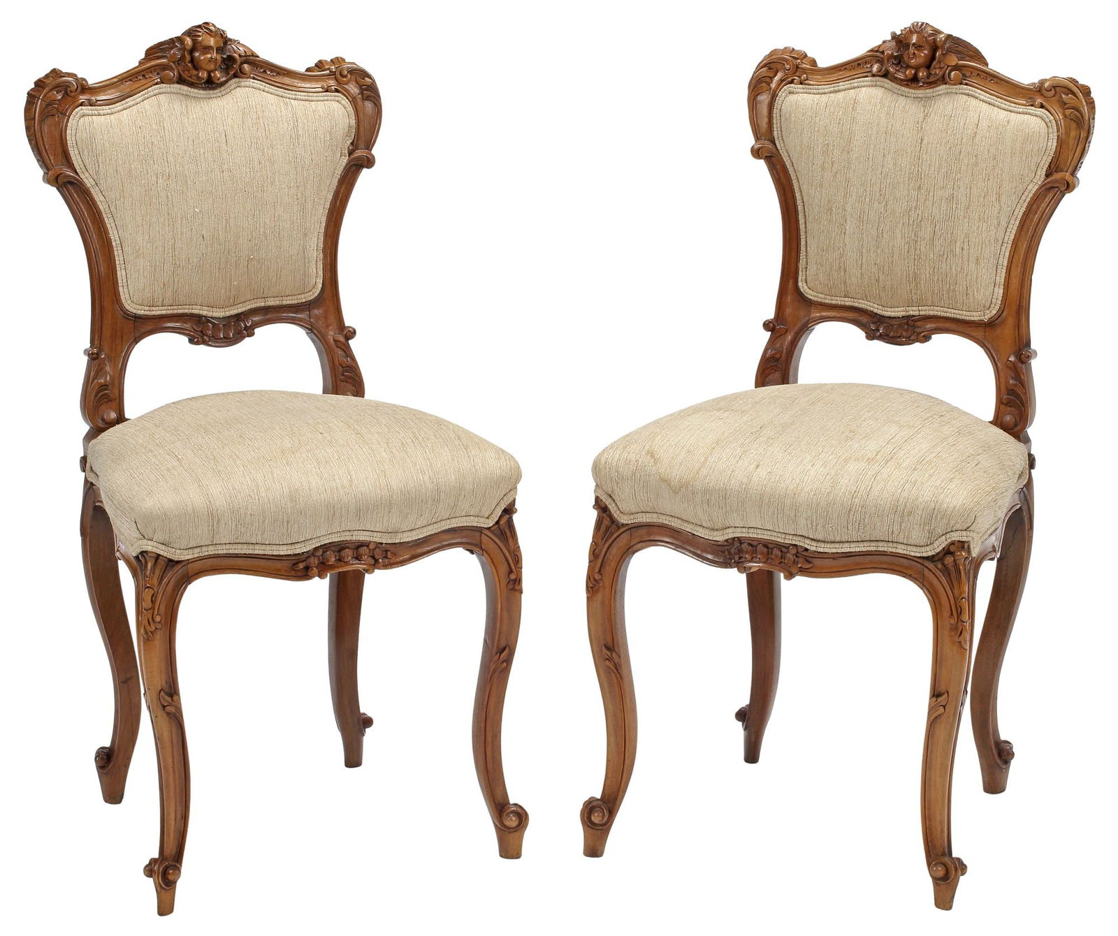 (2) LOUIS XV STYLE CARVED WALNUT MUSIC / SIDE CHAIRS: (pair) Louis XV style carved walnut music or hall chairs, each having cherub mask crest, above padded back and seat in beige linen upholstery, rising on cabriole legs, ending on whorl feet, approx 34"