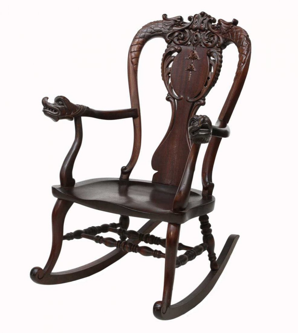 AMERICAN MAHOGANY DRAGON CARVED ROCKER: American mahogany rocking chair, c. 1900, a foliate carved central crest held in the mouths of flanking dragons over the shaped and pierced back splat, curved arms terminating in large dragons heads, 