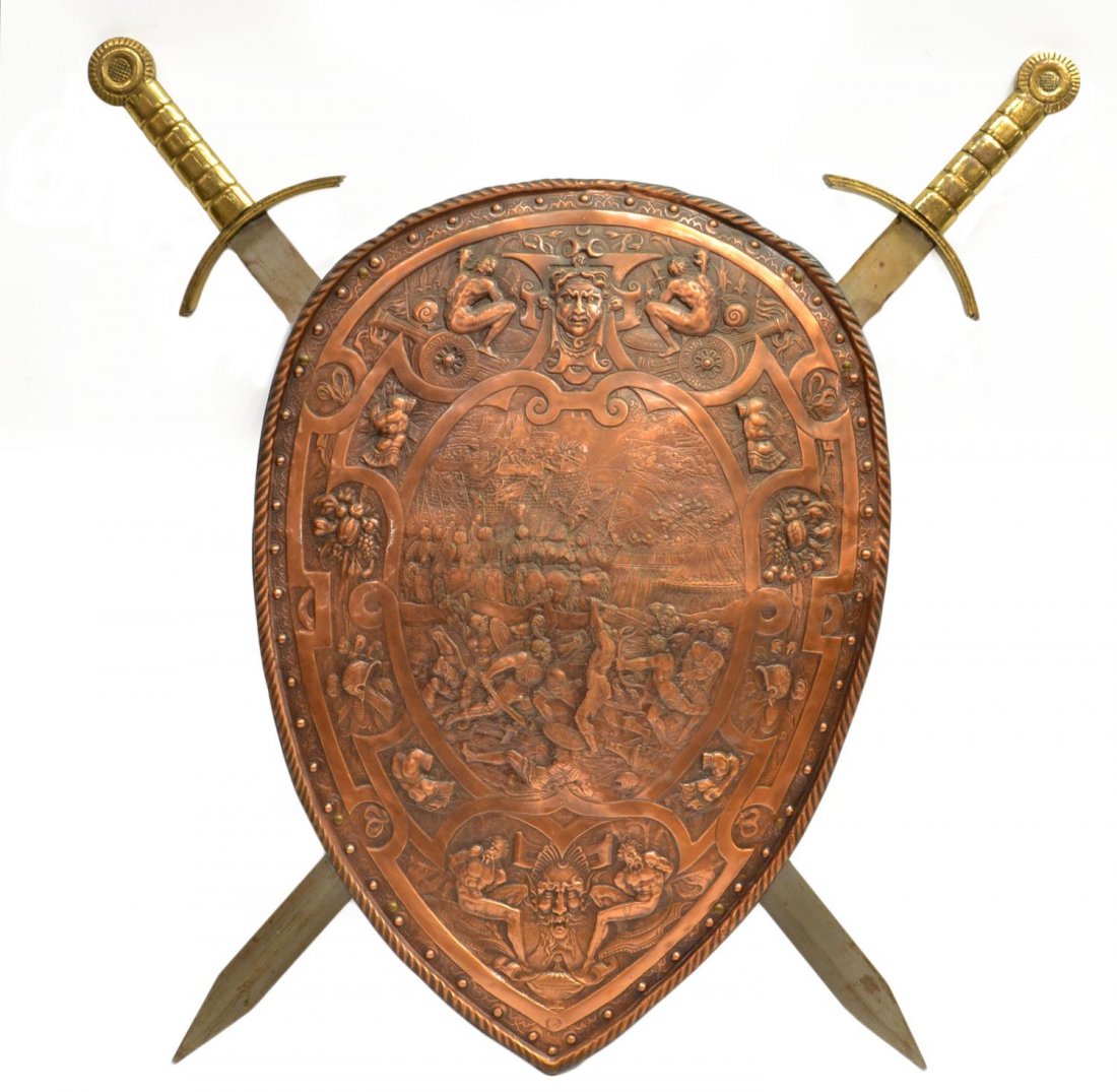 VINTAGE BELGIAN EMBOSSED COPPER SHIELD & SWORDS: Vintage Belgian embossed copper shield fronting crossed swords, classical depiction of a battle scene, surrounded by fruits, figures and masques, retaining partial makers tag verso, shield: 24.75"; sw