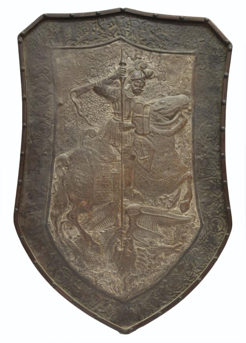 EMBOSSED IRON SHIELD OF SAINT GEORGE & THE DRAGON: Embossed iron shield depicting Saint George thrusting a spear into a dragon's mouth, surrounded by figural scenes, portrait medallions, drums, and other symbols, minor fissure, oxidation verso, 27.75"