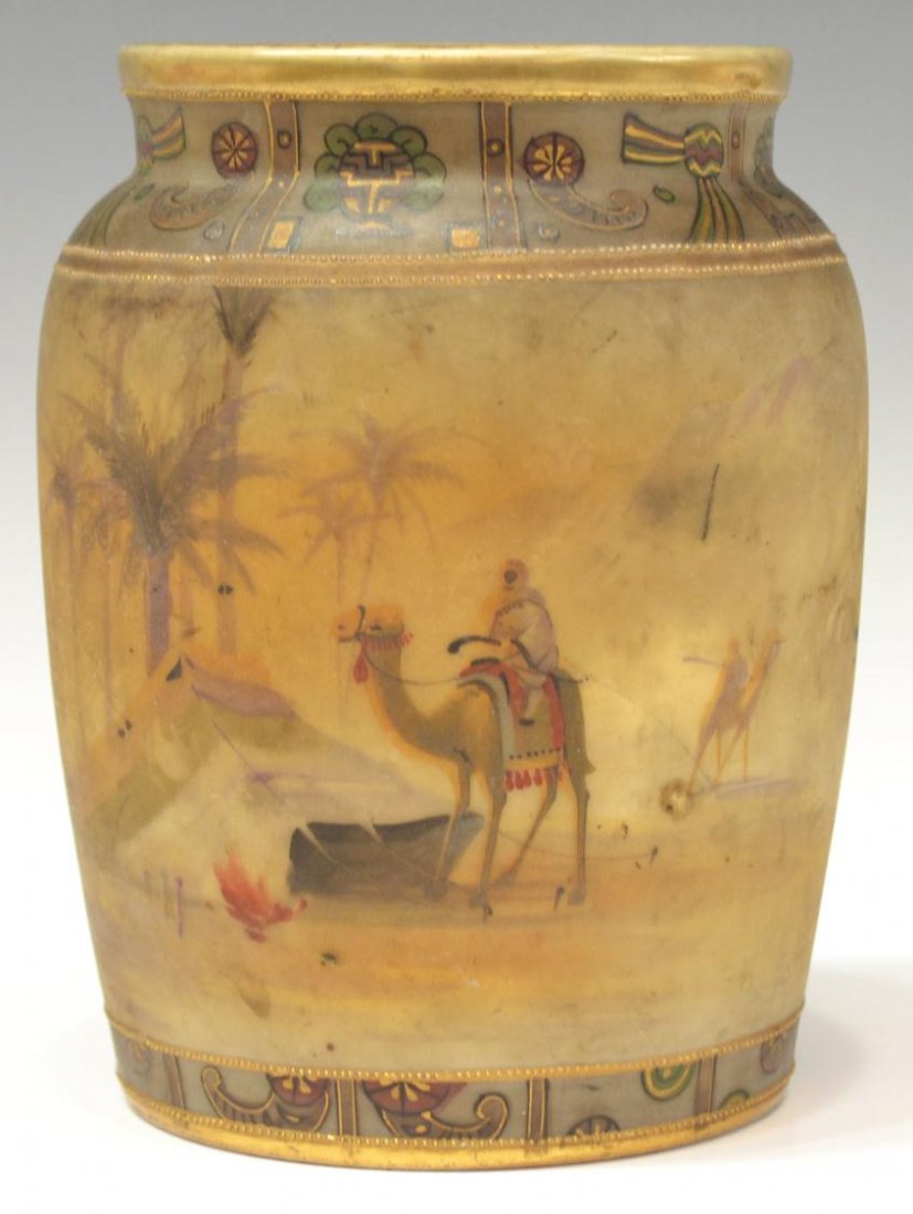 NIPPON EGYPTIAN REVIVAL ORIENTALIST SCENE VASE: Nippon Egyptian Revival porcelain vase with gilded moriage accents, an Orientalist scene hand painted with figures and camels amid a desert landscape, borders of polychrome decoration at base and rim,