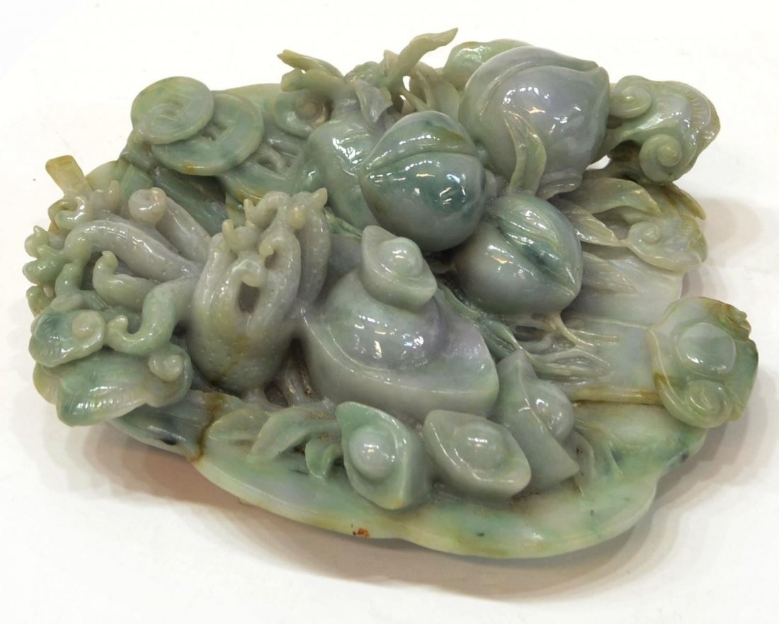 CHINESE RELIEF CARVED JADE OFFERING PLATE: Chinese jadeite relief carving of auspicious objects, 20th c., comprising ingots, peaches, Buddha hand citron, ruyi fungus and cash emblems in a tray with a stylized medallion to the base, 7"l, 6.5"w,