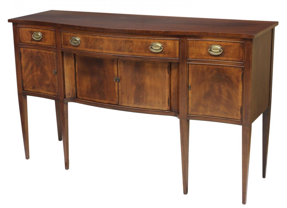 MAHOGANY HEPPLEWHITE STYLE SIDEBOARD: Mahogany Hepplewhite style sideboard, Hickory Chair Company, North Carolina, 20th c., a shaped top over three frieze drawers, two lower central doors flanked by end doors, all rising on tapered square