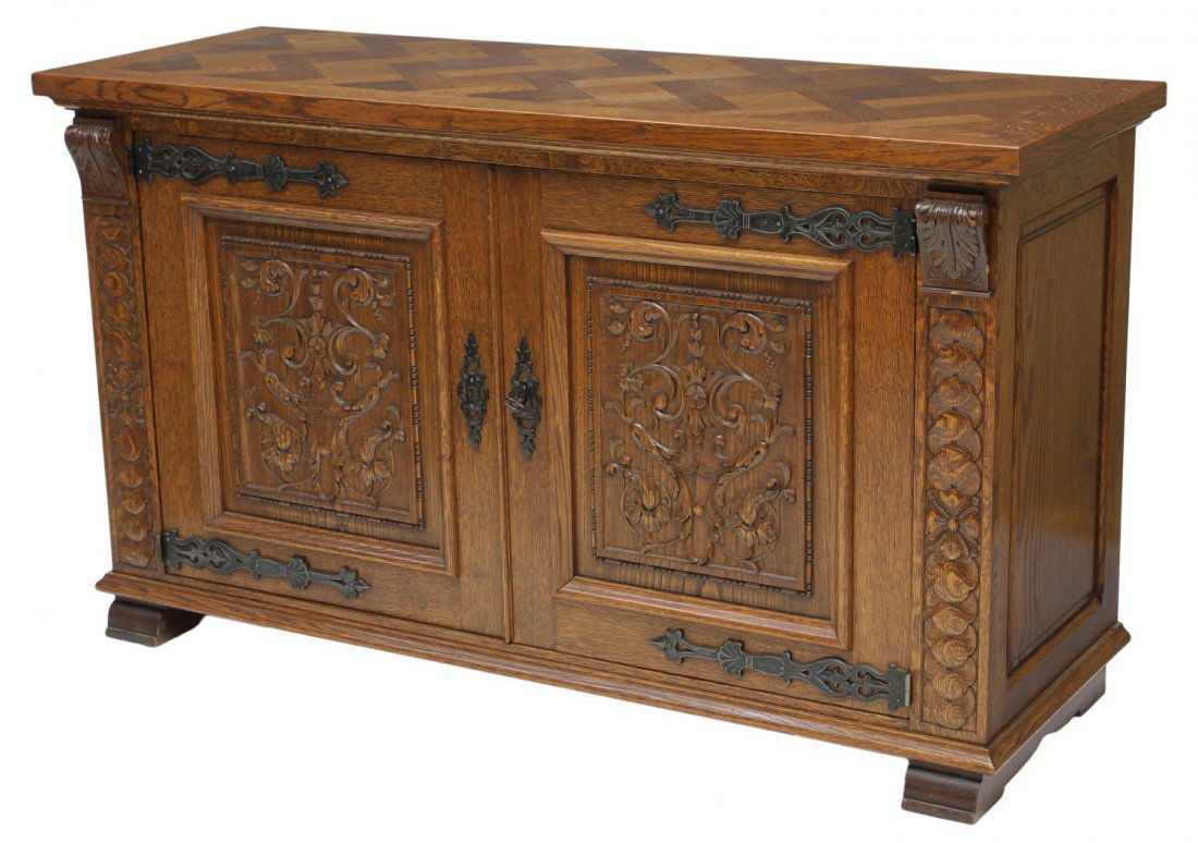 SPANISH FOLIATE CARVED SIDEBOARD: Spanish style oak sideboard or credenza, c. 1900, a rectangular parquetry top over two doors with foliate carved panels opening to shelves, iron strap hinges, shaped block feet, Monaco tag on interior
