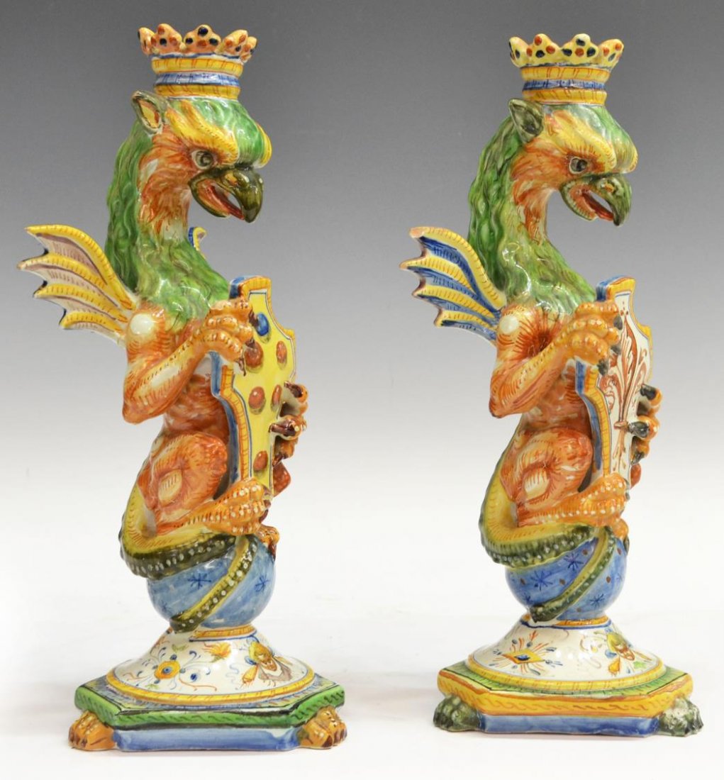ULISSE CANTAGALLI MAJOLICA GRIFFIN CANDLESTICKS: (pair) Italian Ulisse Cantagalli figural earthenware candlesticks, late 19th c., crowned and winged griffins grasp heraldic shields, on a starred globe, tripartite paw foot base, adorned with putti ma